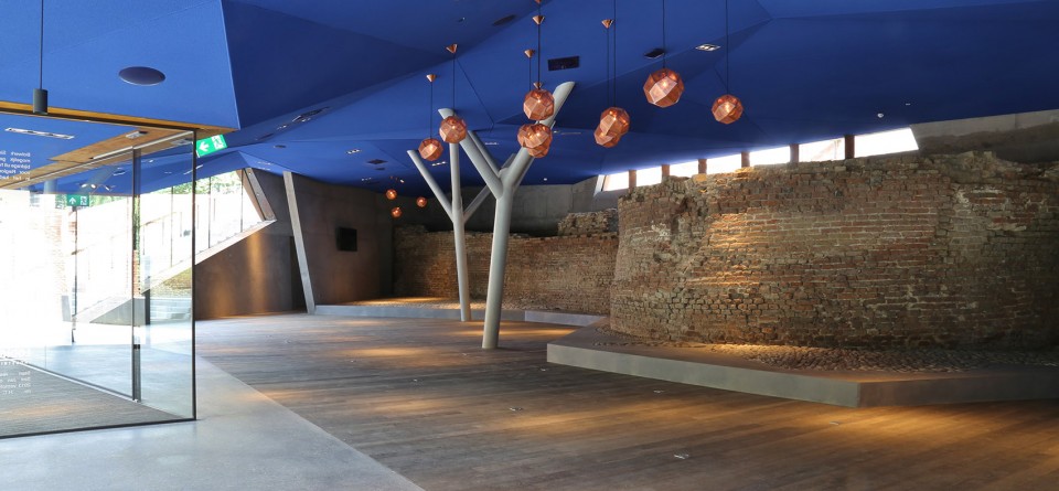 弯曲的支柱支撑着折面天花。古迹的残痕断壁被保留。Ceiling supported by branched columns curving over the old wall remnants. (photo: Tekton Bouwmanagement)