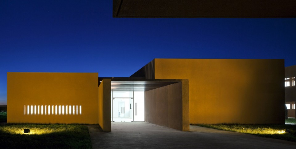 某教学建筑的入口夜景,建筑形体简练有变,开窗克制与气候协调