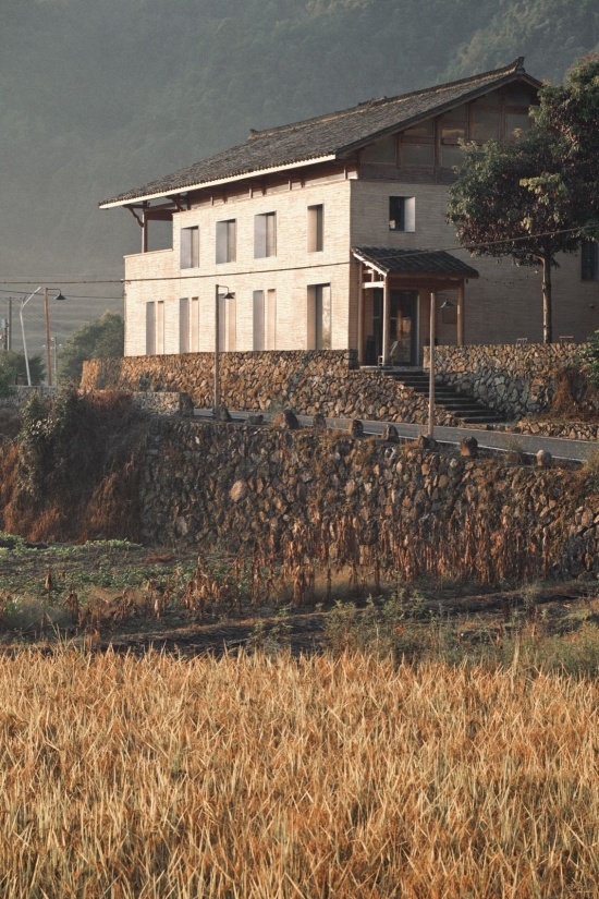 秋日清晨,日出的金光照亮夯土墙和稻田 / Golden sunrise illuminating rammed-earth walls and rice fields on an autumn morning