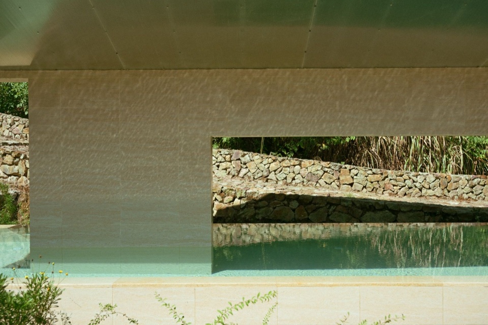 水波反光倒映在片墙上,片墙框景背后是上山的石径 / Rippling light on a freestanding wall framing the stone path uphill