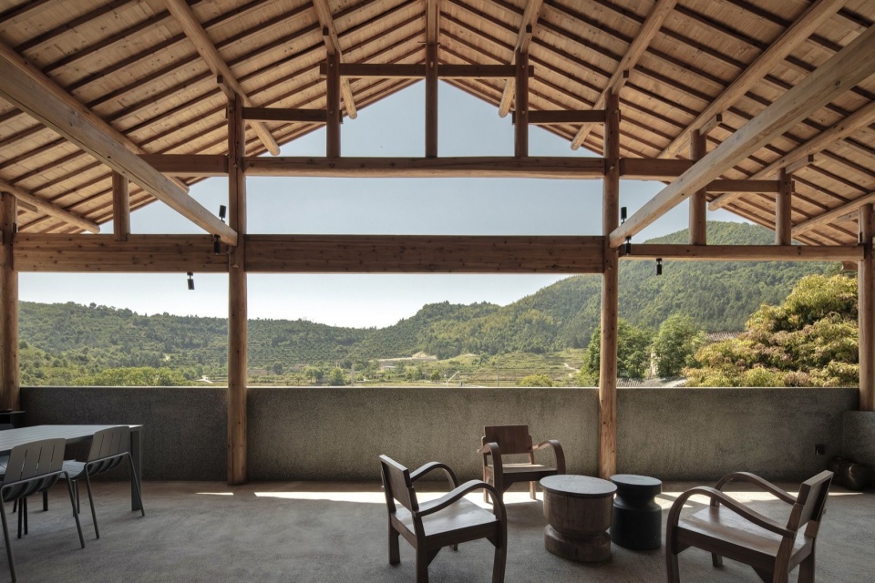 大屋面下的庇护空间——25号楼咖啡厅外侧的二层木屋架下,我们设计了一个相对开敞的露台灰空间,可以眺望远山和梯田 / A sheltered terrace beneath the second-floor timber roof outside Building 25’s café, overlooking distant mountains and terraces