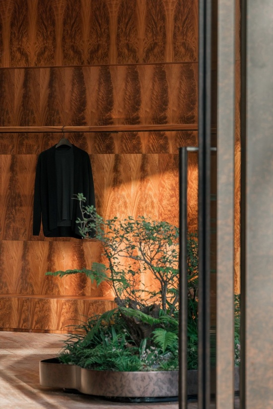 晨光下的洞石地面、木皮墙面与植物池 / Travertine flooring, timber veneer wall lining, and the planter in the morning light