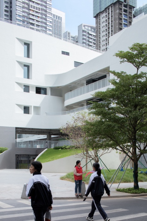 从社区公园望向建筑底部的绿植坡地 / view from the community park toward the green slope