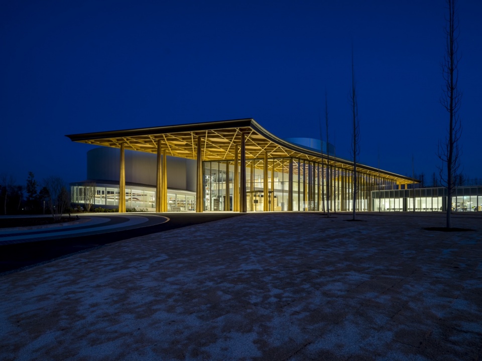 灯光下的木构屋檐与广场夜景 / night view of the lit timber canopy and the plaza
