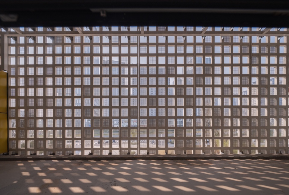 阳光透过建筑外立面方格在室内形成斑驳的光影 / Sunlight filtering through the facade grid casts dappled light and shadow indoors